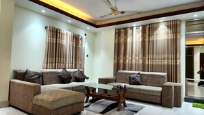 A modern living room with a sectional sofa, a glass coffee table, and a ceiling fan.