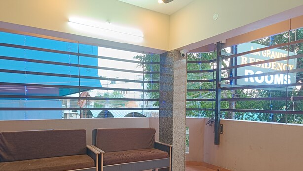 A hotel room with a large window, a blue awning, and a sign reading "LA GRANDE RESIDENCY ROOMS". - La Grande Residency (Puducherry)