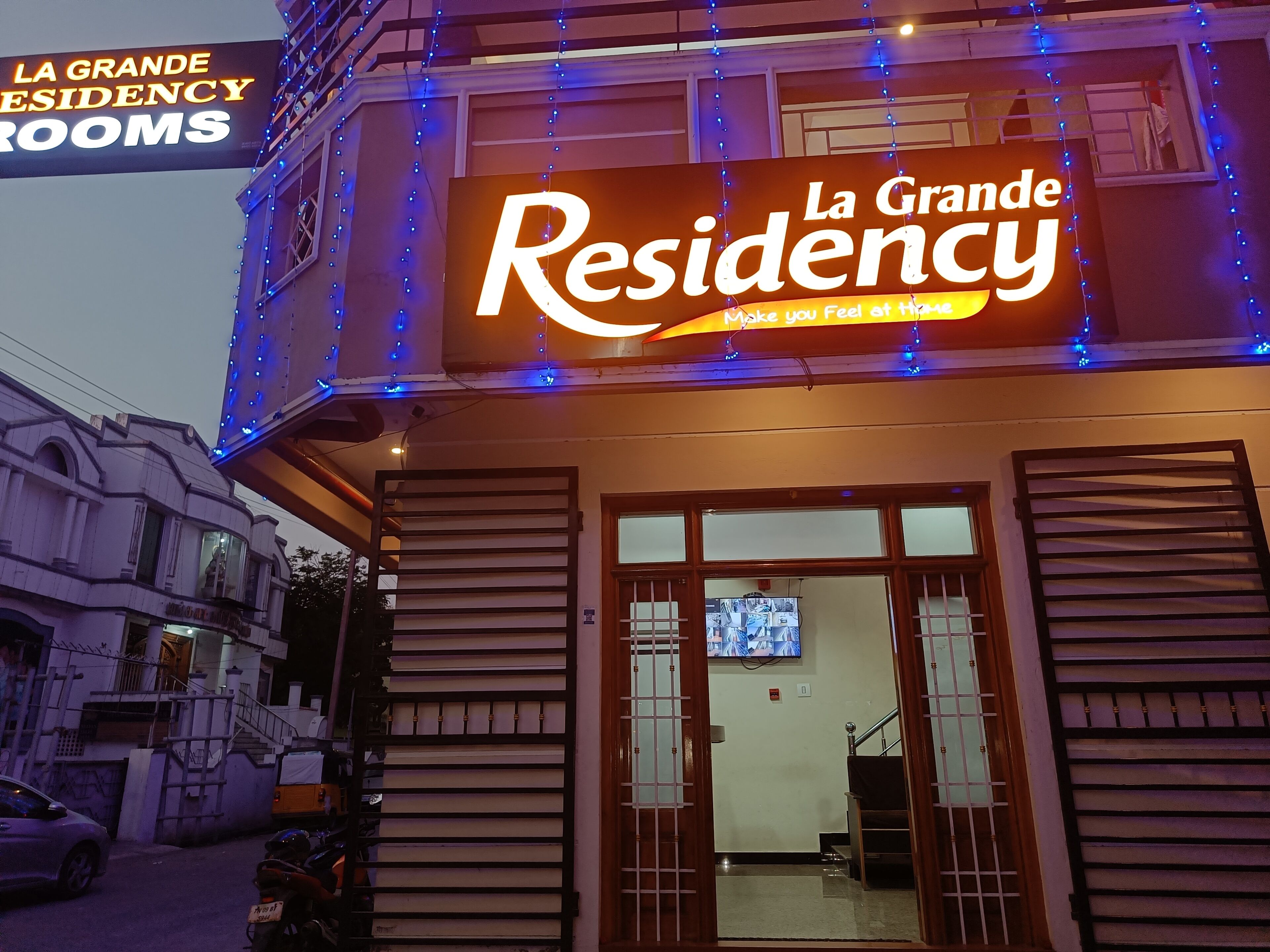 Um edifício com uma placa que diz "La Grande Residency" e uma placa menor acima com a inscrição "La Grande Residency Rooms".