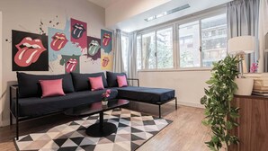 A modern living room with a black sectional sofa, a geometric rug, and a large window with curtains. - MOT Rentals + Casa Chic - 9 Lux Units 36 pax (Palermo Chico)