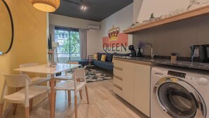 A compact kitchen with a washing machine, a dining area with chairs, and a sofa. - MOT Rentals + Casa Chic - 9 Lux Units 36 pax (Palermo Chico)