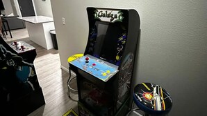 Une pièce équipée d’une console de jeux, d’une petite table avec des collations et d’un tapis de jeu aux couleurs vives.