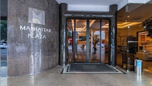 The entrance to Manhatten Plaza with a tiled facade and a glass door entrance. - OZPED Flats Particulares Manhattan (Brasília)