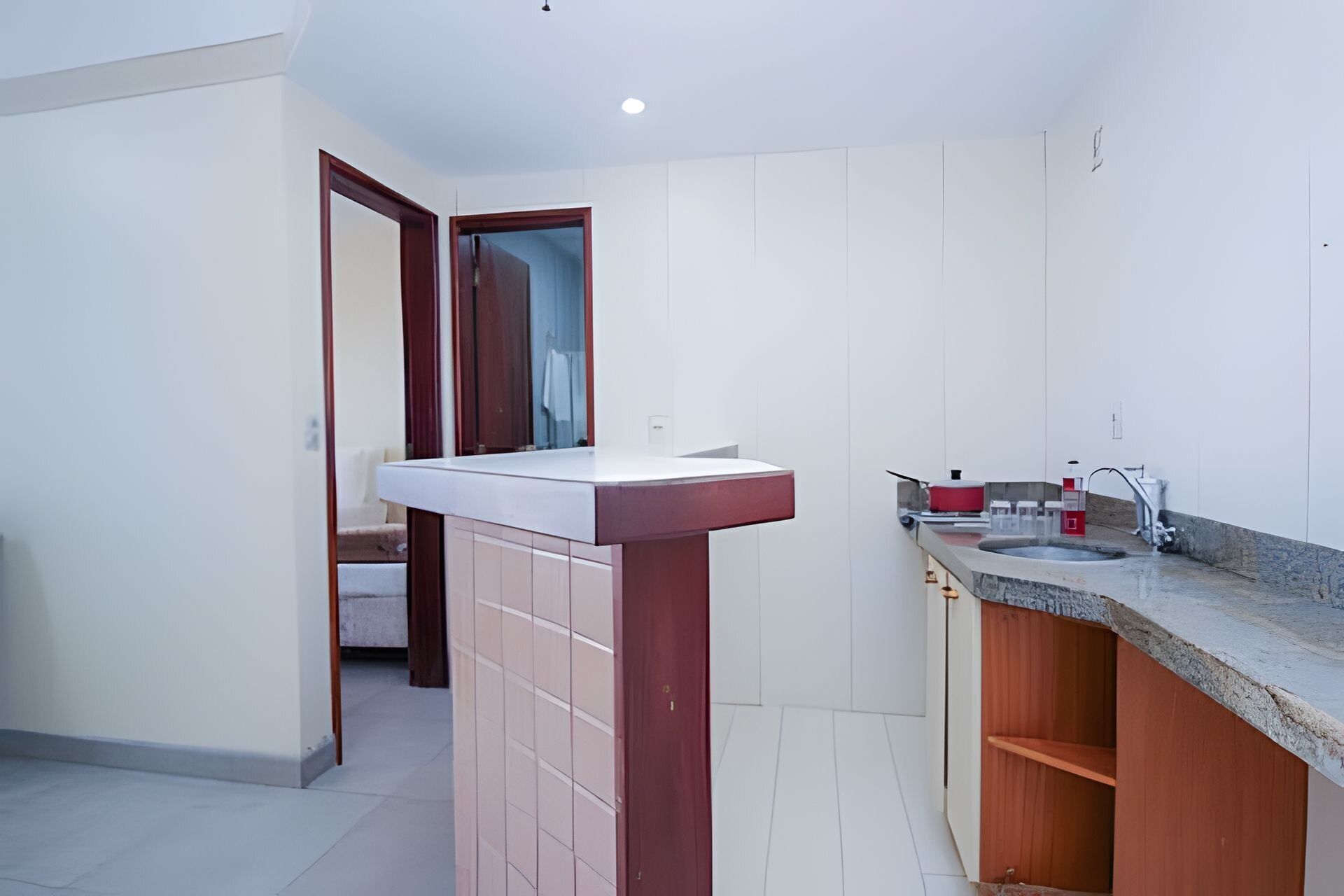 A modern kitchen with a white countertop, a sink, and a red fire extinguisher.