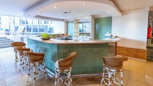 A modern kitchen with a curved island, bar stools, and a view of the outside. - OZPED Flats Particulares Manhattan (Brasília)