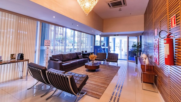 A modern lobby with a leather sofa, a coffee machine, and a chandelier. - OZPED Flats Particulares Manhattan (Brasília)