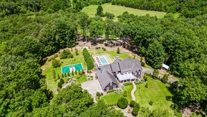 An aerial view of a large estate with a swimming pool, tennis court, and a large house surrounded by dense forest. - Mountain Mansion 7BR, 10Ksf, Views, Pool, Sport Court, Gym, Sauna, Petting Zoo (Blue Ridge)