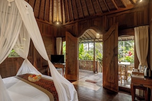 A room with a bed, a television, a dining area, and a view of the outdoors. - Keraman Suite Ubud (Tegallalang)