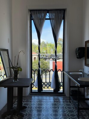 Un baño con vista a un tren y follaje exterior.