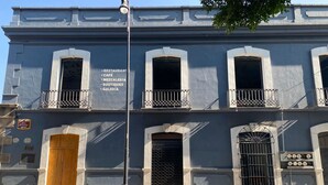 Un edificio con múltiples ventanas y balcones, que presenta carteles para un restaurante, un café y una galería.