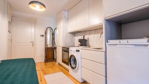 A compact kitchen with a washing machine, oven, and a coffee machine. - Taipas Tranquility: Cozy T0 by LovelyStay (Porto)
