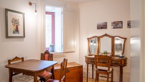 A dining area with a wooden table and chairs, a dresser with a mirror, and a window with a view of the outdoors. - Taipas Tranquility: Cozy T0 by LovelyStay (Porto)