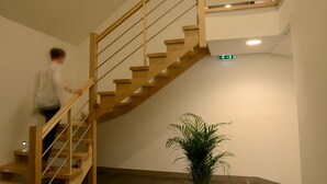 Een houten trap met een leuning, een bord met de tekst 