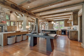A spacious kitchen with wooden beams, a large island, and a stone fireplace. - Silverfell Lodge at Northstar - TLUXP (Truckee)
