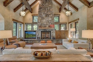 A spacious living room with a stone fireplace, leather sofas, a television, and a stone accent wall. - Silverfell Lodge at Northstar - TLUXP (Truckee)