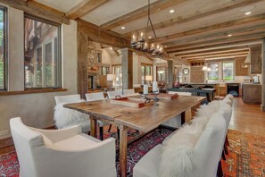 A spacious dining area with a long wooden table, white upholstered chairs, and a chandelier. - Silverfell Lodge at Northstar - TLUXP (Truckee)