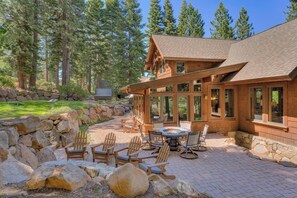 A lodge with a stone patio, wooden chairs, and a fire pit. - Silverfell Lodge at Northstar - TLUXP (Truckee)