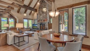 A spacious living area with a fireplace, large windows, and a stone accent wall.