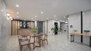 A modern hotel lobby with a reception desk, seating area, and potted plants. - Mons Boutique Hotel and Apartment  (Da Nang)