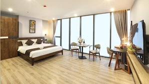 A modern hotel room with a large bed, a dining area, and a TV. - Mons Boutique Hotel and Apartment  (Da Nang)