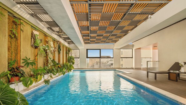 An indoor swimming pool with a wooden ceiling, tiled floor, and potted plants along the walls. - Mons Boutique Hotel and Apartment  (Da Nang)