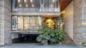 A modern building with a glass facade, a staircase, and a large potted plant. - Mons Boutique Hotel and Apartment  (Da Nang)