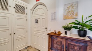 Een gang met witte deuren, een houten kast, een kamerplant en een bord aan de muur.