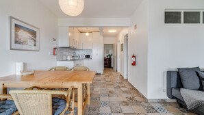 Une cuisine moderne avec des meubles blancs, une table à manger en bois et un sol carrelé à motifs.