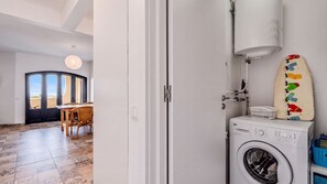 Een wasruimte met een wasmachine, een droogrek en een vrolijke surfboarddecoratie.