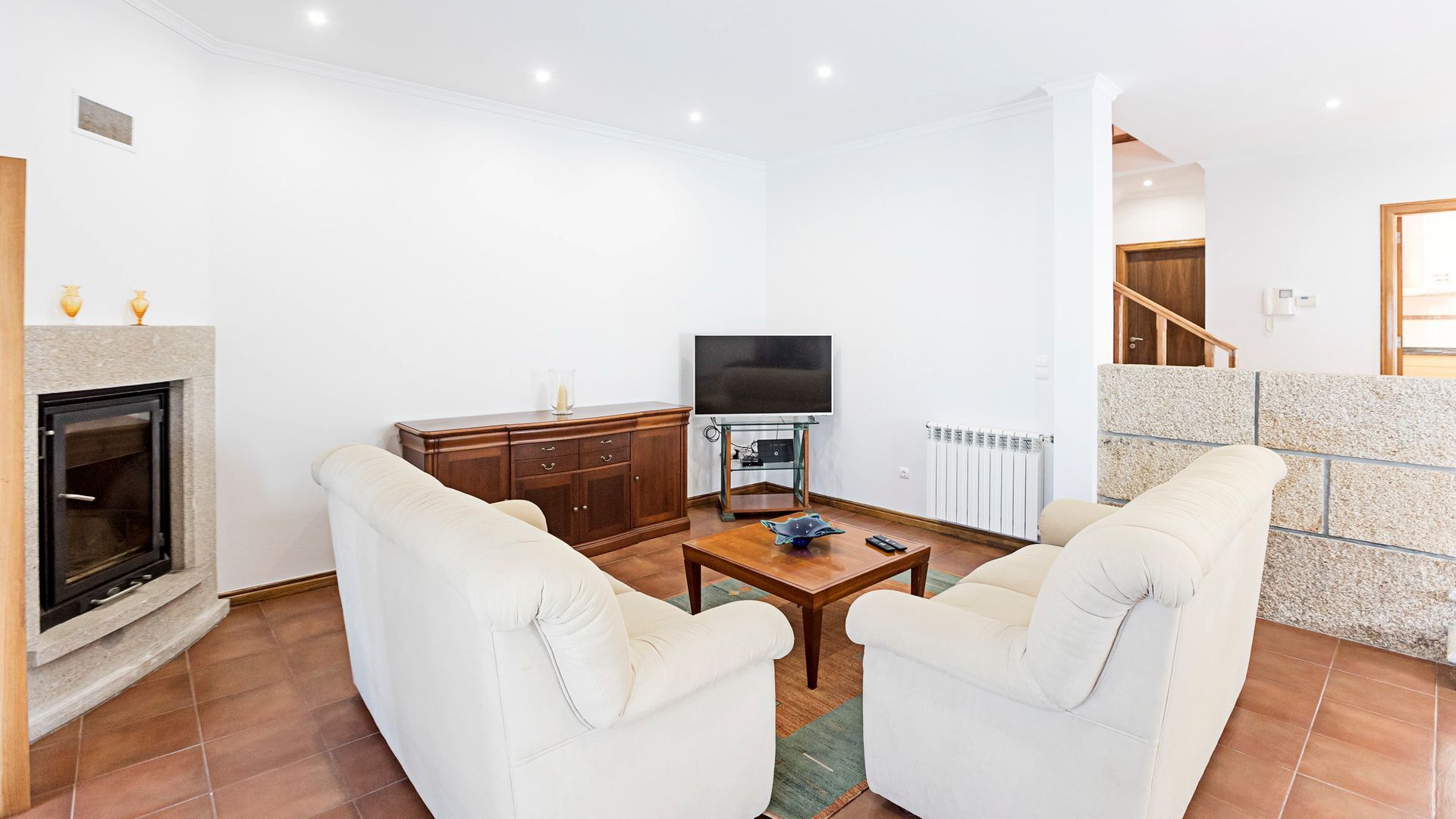 Ein Wohnzimmer mit Kamin, Fernseher und zwei Sofas.