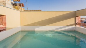 Enjoy a refreshing swim in our rooftop pool surrounded by a flat rooftop and a part of the building.
