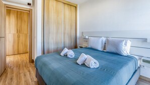 Una habitación de hotel con una cama, un armario y una mesita de noche.