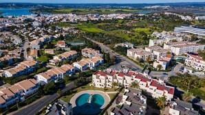 Zona residencial con una gran piscina, varios edificios de apartamentos y una calle.