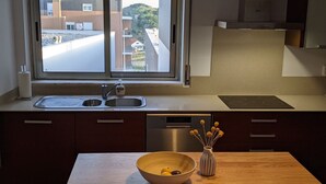 Una cocina moderna con un lavamanos doble, electrodomésticos de acero inoxidable y vistas a edificios a través de una ventana.