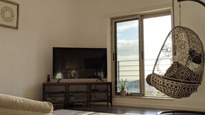 Una sala de estar con un televisor de pantalla plana grande, un sillón colgante y vistas al exterior a través de un ventanal amplio.