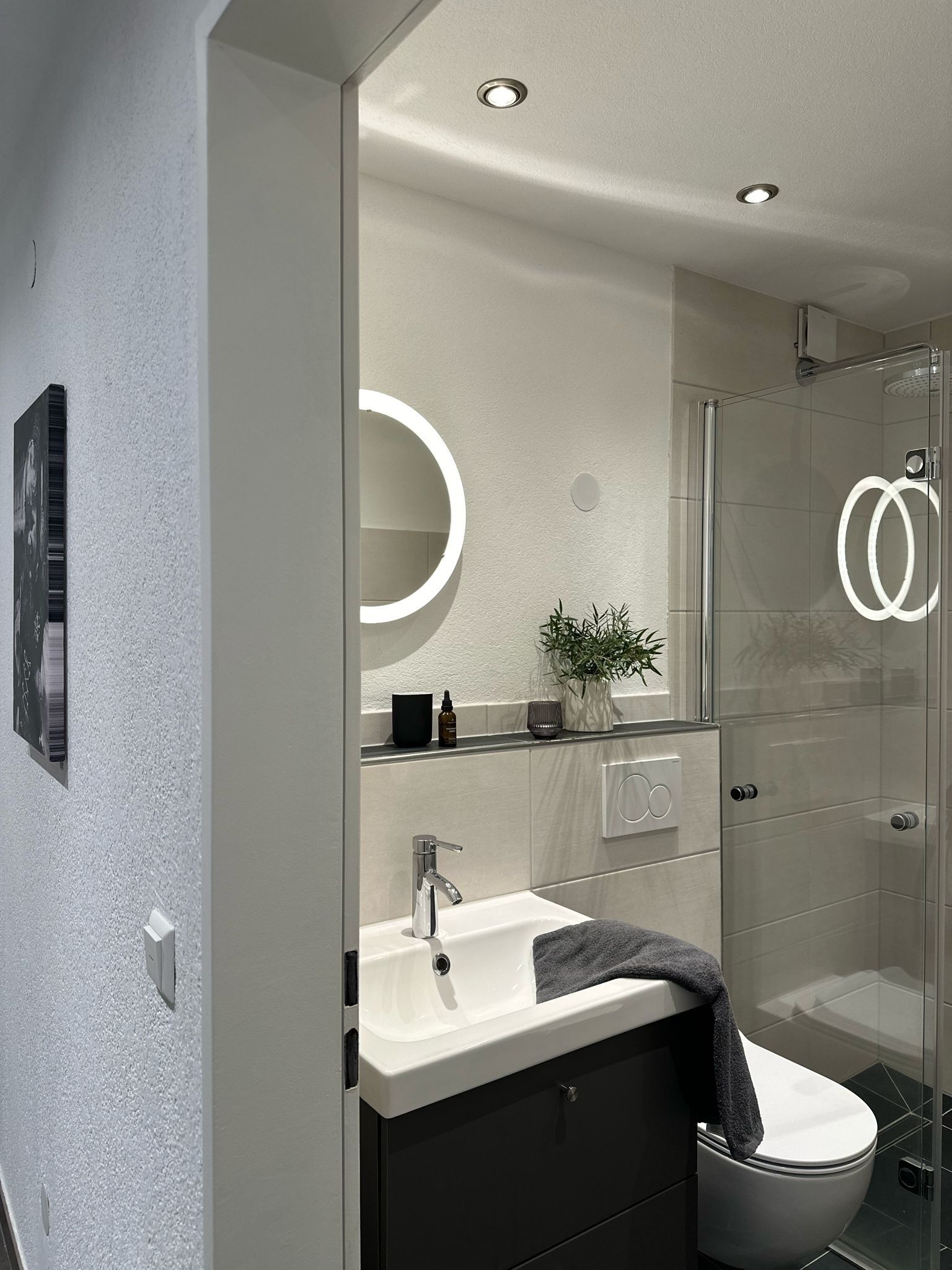 Un baño moderno con cabina de ducha de vidrio, lavamanos blanco y retrete.
