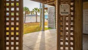 An entrance to a property with a wooden lattice gate and a 'No Trespassing' sign. - Beachside Breeze: Modern Condo in Walking Distance to Beach, Dining, Shops (Oak Island)