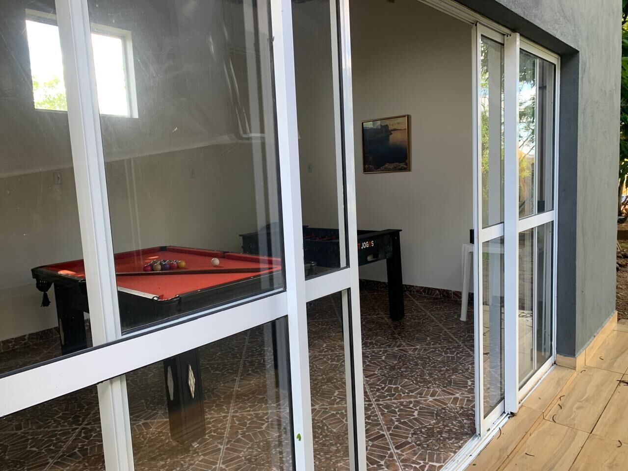 Une table de billard recouverte d’un drap de feutre rouge, un queue de billard et une table noire ornée d’un logo.