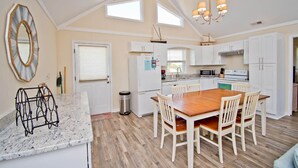 A kitchen with white cabinets, a wooden dining table, and a chandelier. - Vitamin Sea, Almost Oceanfront House in Emerald Isle, NC! (Emerald Isle)