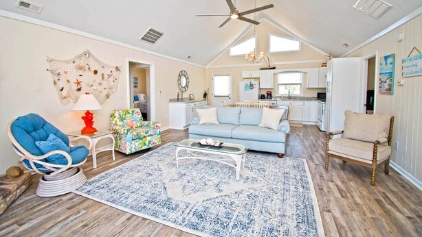 A spacious living room with a high ceiling fan, a blue sofa, a floral armchair, and a glass coffee table. - Vitamin Sea, Almost Oceanfront House in Emerald Isle, NC! (Emerald Isle)