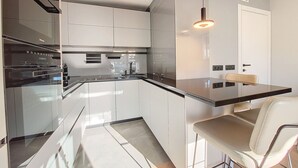 Et moderne køkken med stilfulde skabe, en emhætte i rustfrit stål og en hængende lampe.