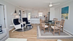 A spacious living area with a dining table, chairs, and a ceiling fan.