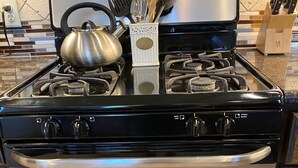 A kitchen with a black stove top oven, stainless steel range hood, and a built-in oven.