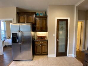 A kitchen with a stainless steel refrigerator, wooden cabinets, a built-in oven, and a pantry door. - Elegant 3BR Home , Fenced Yard & Crews, Nurses, Quiet Neighborhood (Tyler)