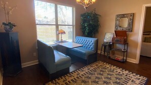 A living room with a blue sofa, a small table, a chandelier, a potted plant, and a patterned rug.