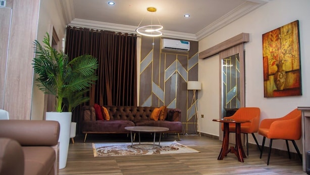 A modern living room with a sofa, two armchairs, a coffee table, and a large potted plant. - Golden Tulip Hotel GT31-Rivotel (Port Harcourt)