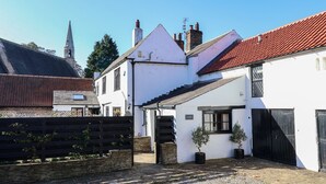 A traditional white building with a red-tiled roof, a wooden fence, and a gravel courtyard. - Old Roost Farmhouse (York)