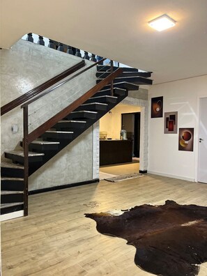 Eine Treppe mit einer Betonwand und einem Holzgeländer, das zu einer Tür führt.