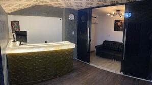 Et receptionområde med reception, et ur og en sofa i baggrunden.