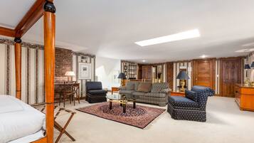 Relax in this inviting living room with a comfortable sofa set, armchair, and coffee table, plus a cozy sleeping area with a four-poster bed.